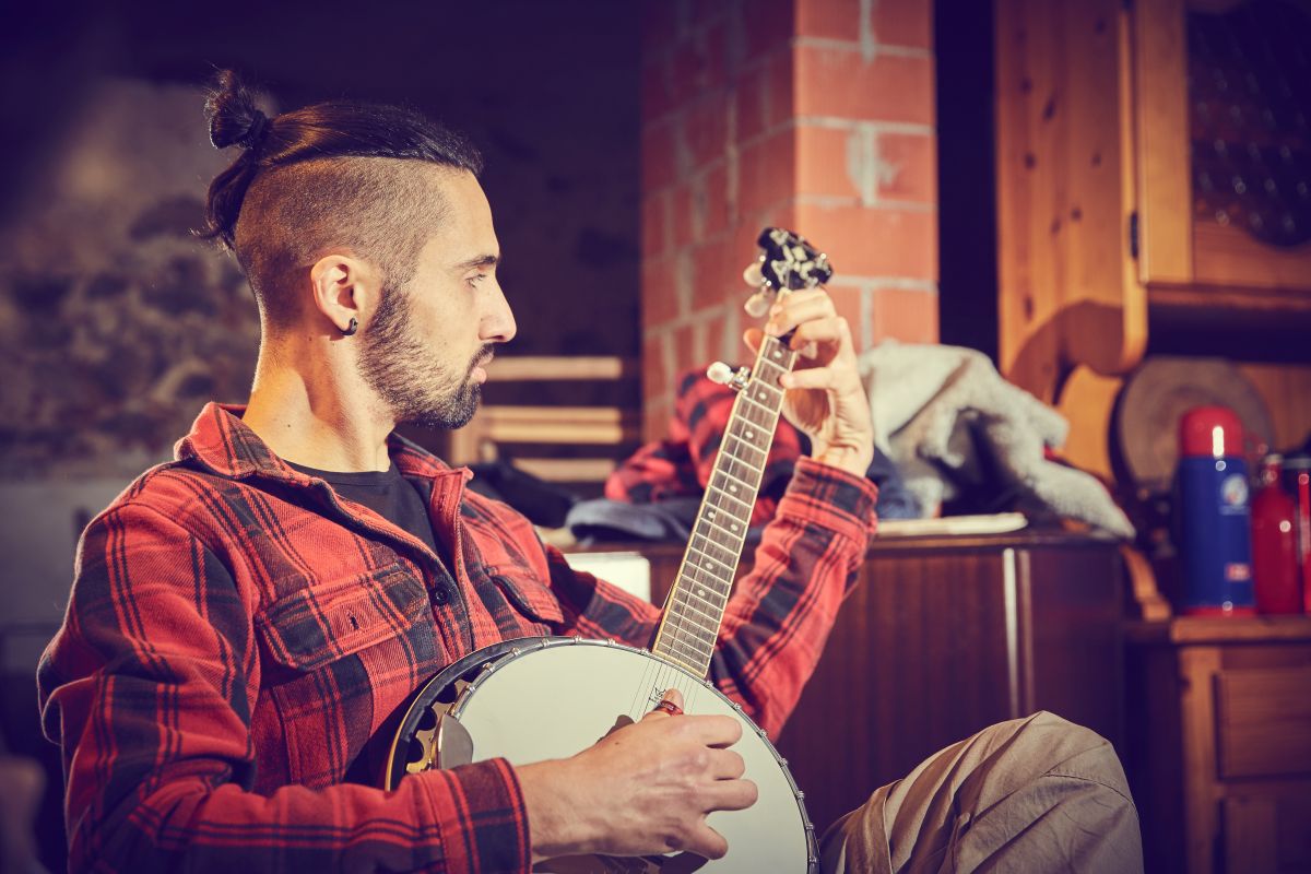 A man learning to play the Banjo at home on the couch
